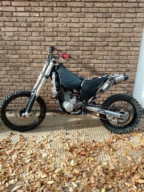 A Dirt Bike Parked In Front Of A Brick Wall With Leaves On The Ground