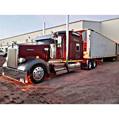 A Red Semi Truck Parked In Front Of A Building With Lights On It S Sides