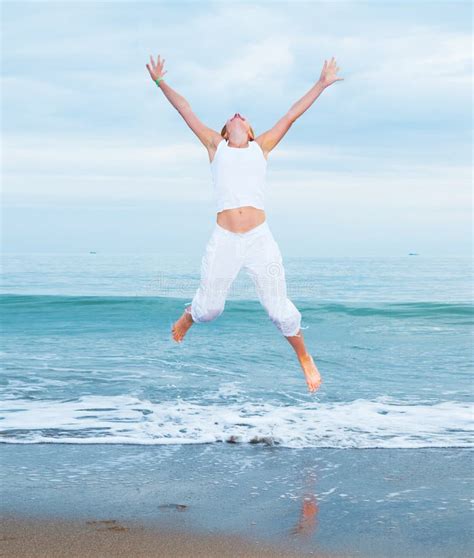 La Mujer Joven Feliz Est Saltando En La Playa Foto De Archivo Imagen