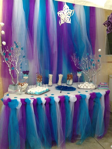 A Table Topped With Cake And Desserts Covered In Blue And Purple Tulle