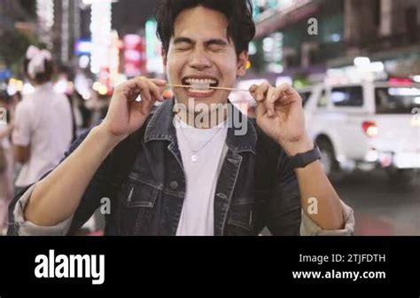 Asian Man Enjoying And Eating Street Food In Night Market With Crowd Of