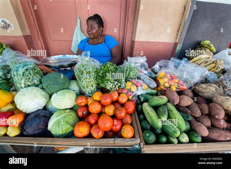 A Woman Selling Colourful Vegetables And Fruit On A Market Stall In