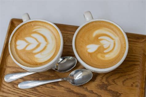 Premium Photo | Two white cups of cappuccino on a wooden tray