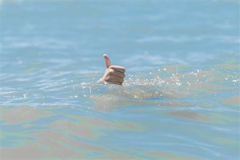 Hand From Under The Water Of A Drowning Girl Shows Class With A Thumb