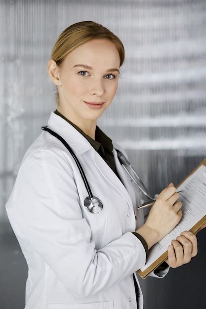 Premium Photo Friendly Smiling Female Doctor Using Clipboard In