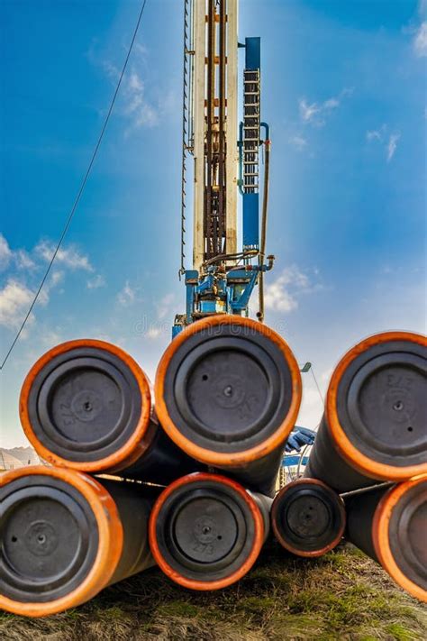 Pipes For A Well Close Up Powerful Drilling Rig Against A Cloudy Sky