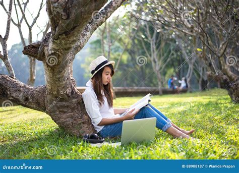 Girl Enjoy Reading A Book Under The Tree Laying On Grass Of Park Stock