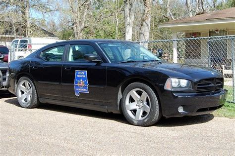 a black police car parked in front of a house with a sign on the door