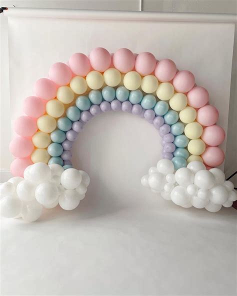 A Rainbow Balloon Arch With Pastel Colors And White Balloons In The