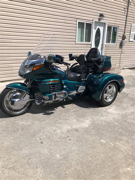 A Blue Motorcycle Parked In Front Of A House With A Side Car Attached To It