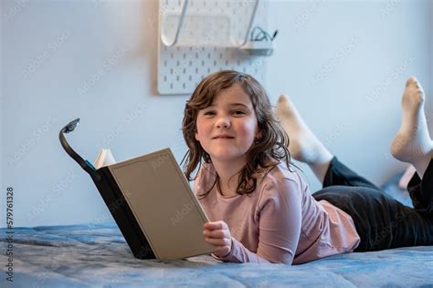 Little girl reading book on bed Stock Photo | Adobe Stock