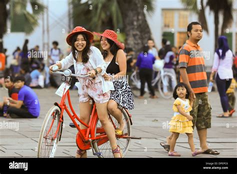 Two Young Indonesian Women Enjoying A Bicycle Ride In Fatahillah Square