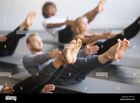 Group Of Young Sporty People Practicing Yoga Lesson With Instructor