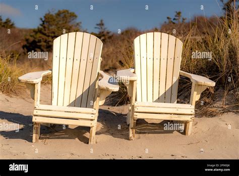 Two White Adirondack Chairs On A Sandy New England Cape Code Beach