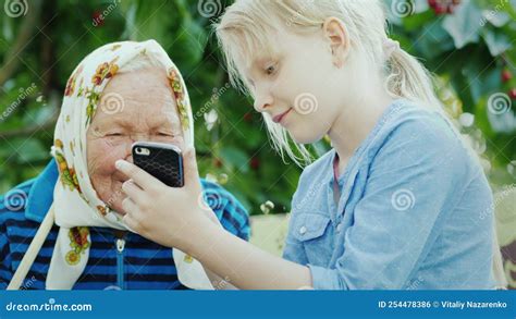 The Girl And Her Grandmother Are Resting On The Summer Veranda The Grandmother Looks At The