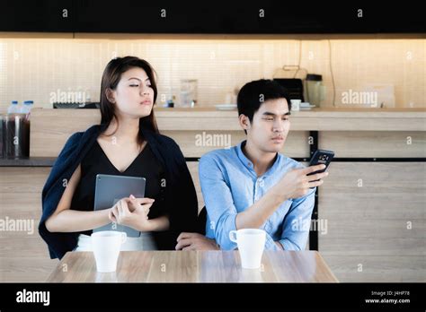 Jeune couple amateur asiatique using smartphones au café Petite amie jalouse peeking pour