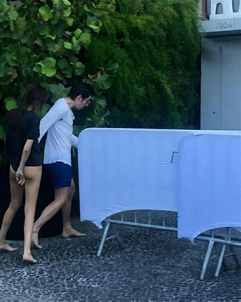 Two People Walking Past A Table With Chairs On It