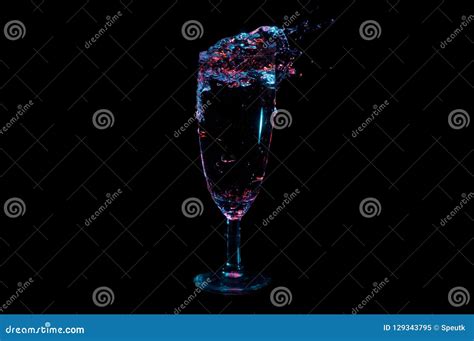 Clear Beverage Spilling Out Of A Tall Clear Glass With A Stem Isolated On A Black Background