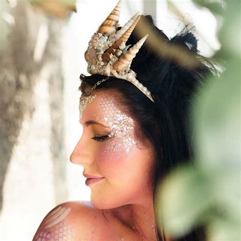 A Woman With White Glitter On Her Face Wearing A Tiara And Shell Headdress