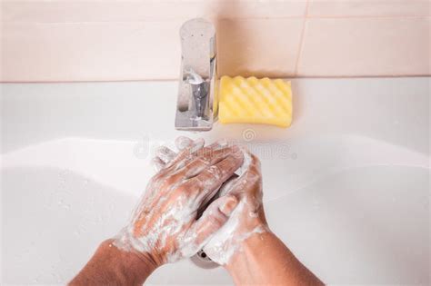 Man Washing Hands With Soap Under Faucet In Bathroom Stock Photo