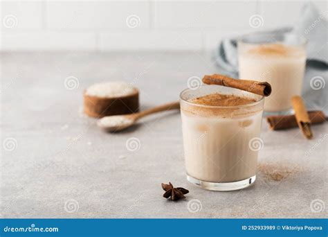 Homemade Horchata Rice Drink In A Glass With Ice And Cinnamon Stick On A Gray Concrete