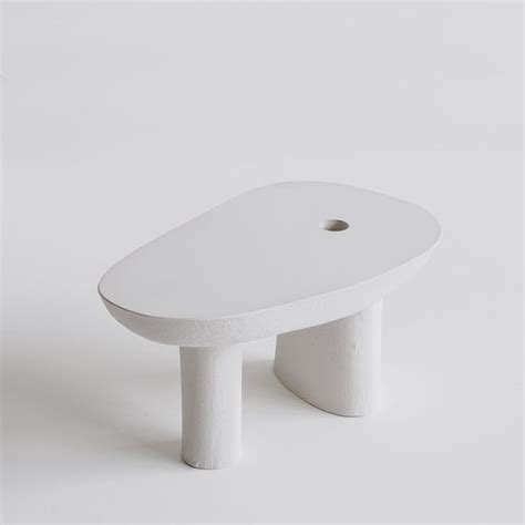 a white stool with a hole in the middle on a plain surface, it appears ...