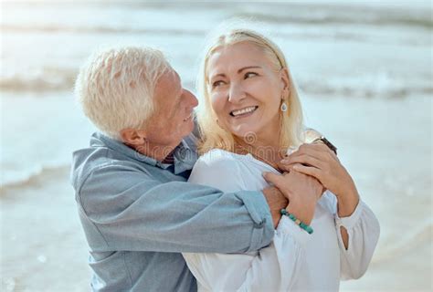 Mature Couple And Hug On Beach With Care On Retirement Vacation