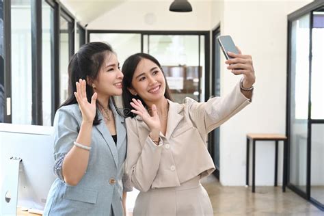 Two Woman Waving Hand While Doing Video Call On Smart Phone Stock