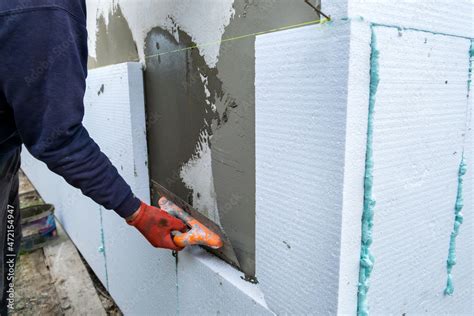 Construction worker installing styrofoam insulation sheets on house ...