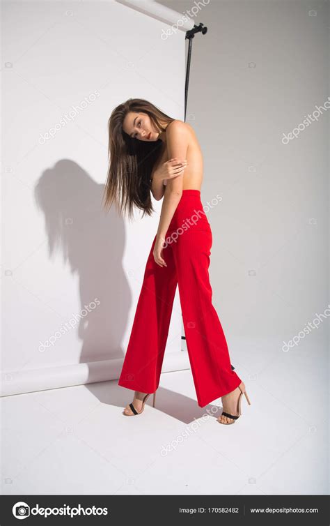 Beautiful Naked Woman In Red Pants Posing Casting Shadow Isolated On