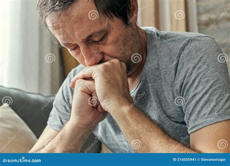 Depressed Sulking Man Sitting Alone At Living Room Sofa And Thinking