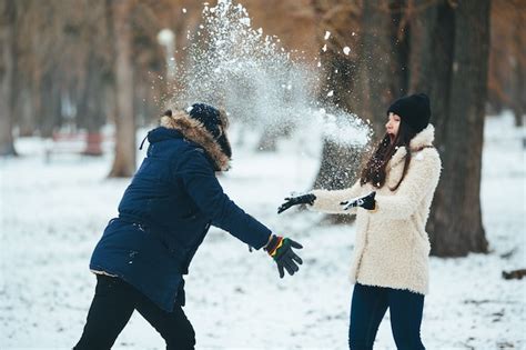 Hombre Joven Lanzando Una Bola De Nieve A Su Amiga Foto Gratis