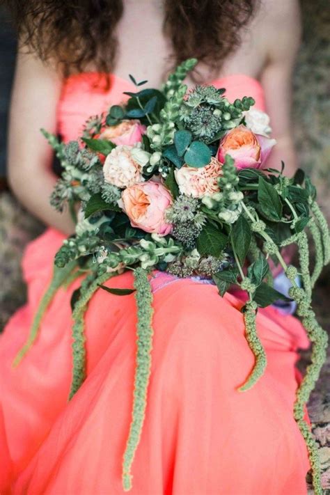 A Woman In An Orange Dress Holding A Bouquet Of Flowers And Greenery On