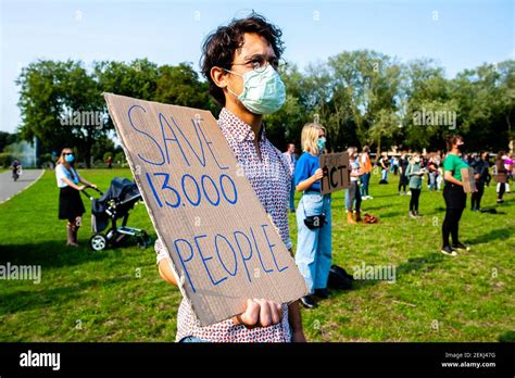 Un Manifestant Portant Un Masque Facial Tient Un Criteau Qui Dit