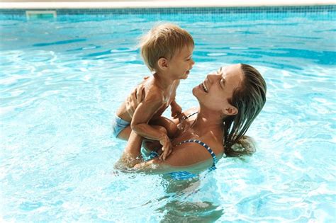 Madre y su pequeño y lindo hijo nadando en la piscina al aire libre