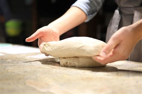 A Person Is Kneading Dough On Top Of A Counter With Their Hands In The Air