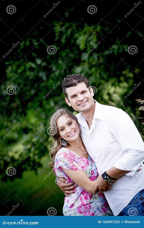 Vertical Shot Of A Happy Couple Hugging Each Other And Smiling At The