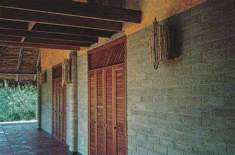 A Row Of Wooden Doors On The Side Of A Brick Building With Grass In The