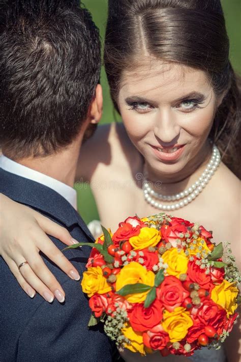 Husband Embracing Her Wife While She Holds A Roses Bouquet In Ha Stock