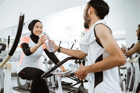 Casal muçulmano se exercitando juntos na academia tomando uma garrafa