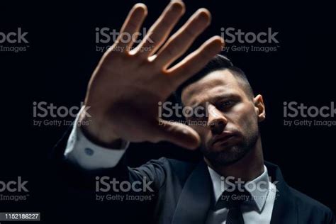 Handsome Man Showing Stop Sign Isolated On Dark Background Stock Photo