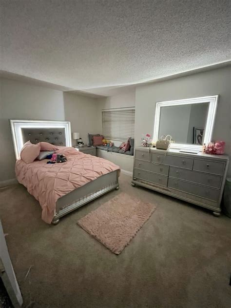 A Bed Room With A Neatly Made Bed And Two Dressers Next To Each Other