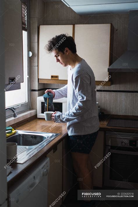 Man In Pajama Pouring Coffee In Cup In Kitchen Cozy Interior Stock