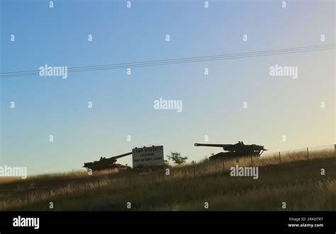 Sign And Two Tanks On The Horizon At Sunset Army National Guard Camp