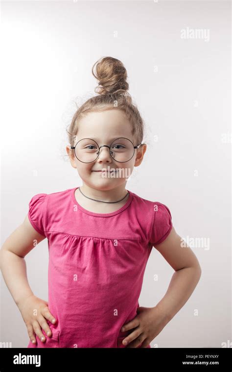 positive smiling girl with hairbun wearing stylish trendy dress, round glasses and chain ...