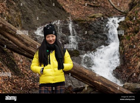 A chinese woman wearing a winter jacket near a waterfall at Rudd Pond ...