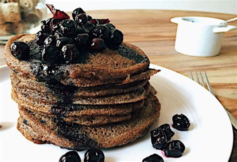 a stack of pancakes topped with blueberries and raisins on a white plate