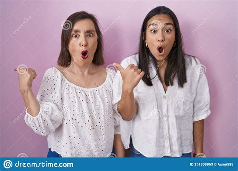 Hispanic Mother And Daughter Together Surprised Pointing With Hand Finger To The Side Open