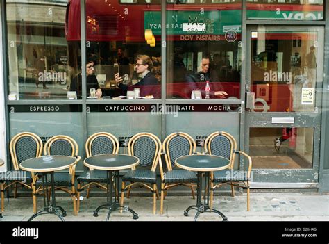 Cafe with empty tables and chairs outside with people inside looking ...