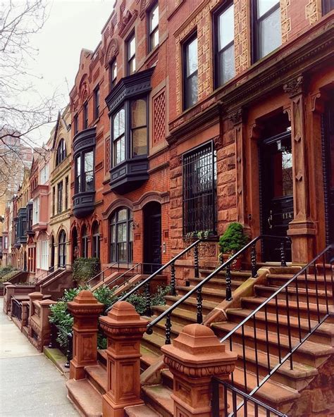 An Old Brick Row House With Many Windows And Balconies On The Side Walk